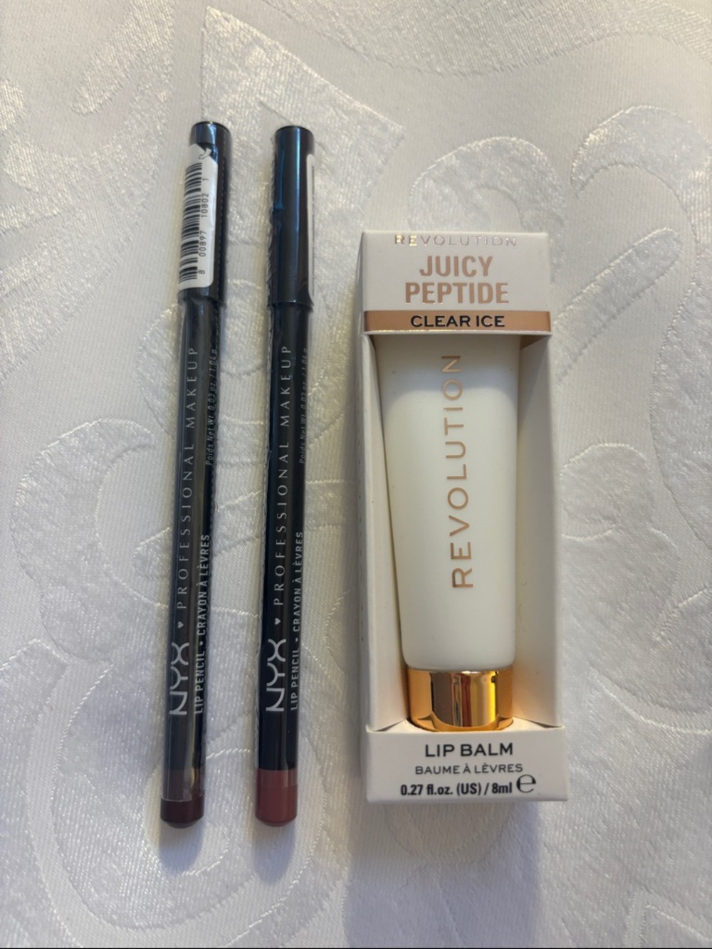 Two NYX lip pencils and Revolution Juicy Peptide clear lip balm